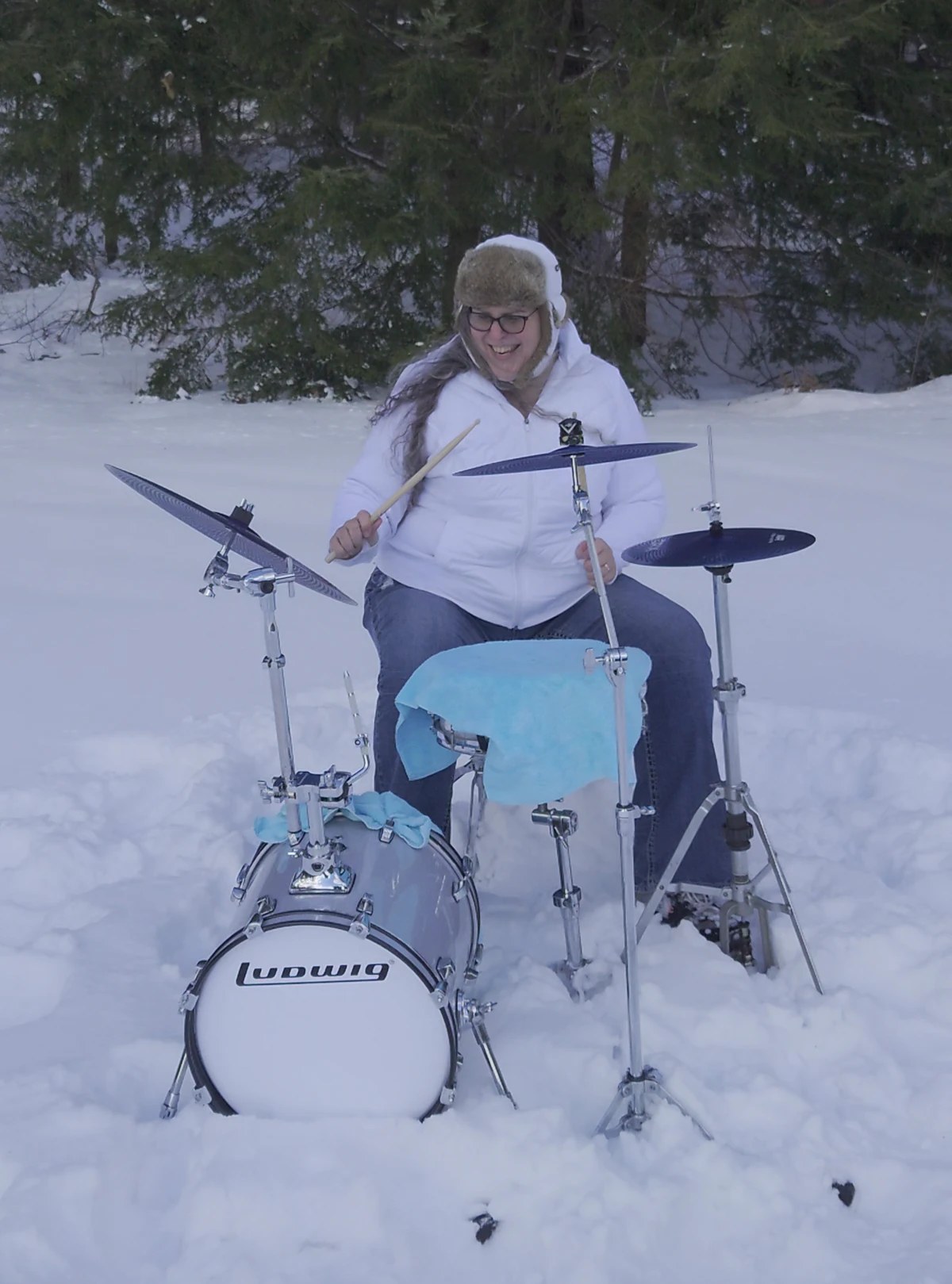 Penny Larson playing drums outdoors in deep snow — because why not