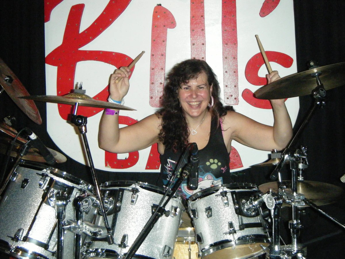 Penny Larson performing live on drum set — dynamic live show